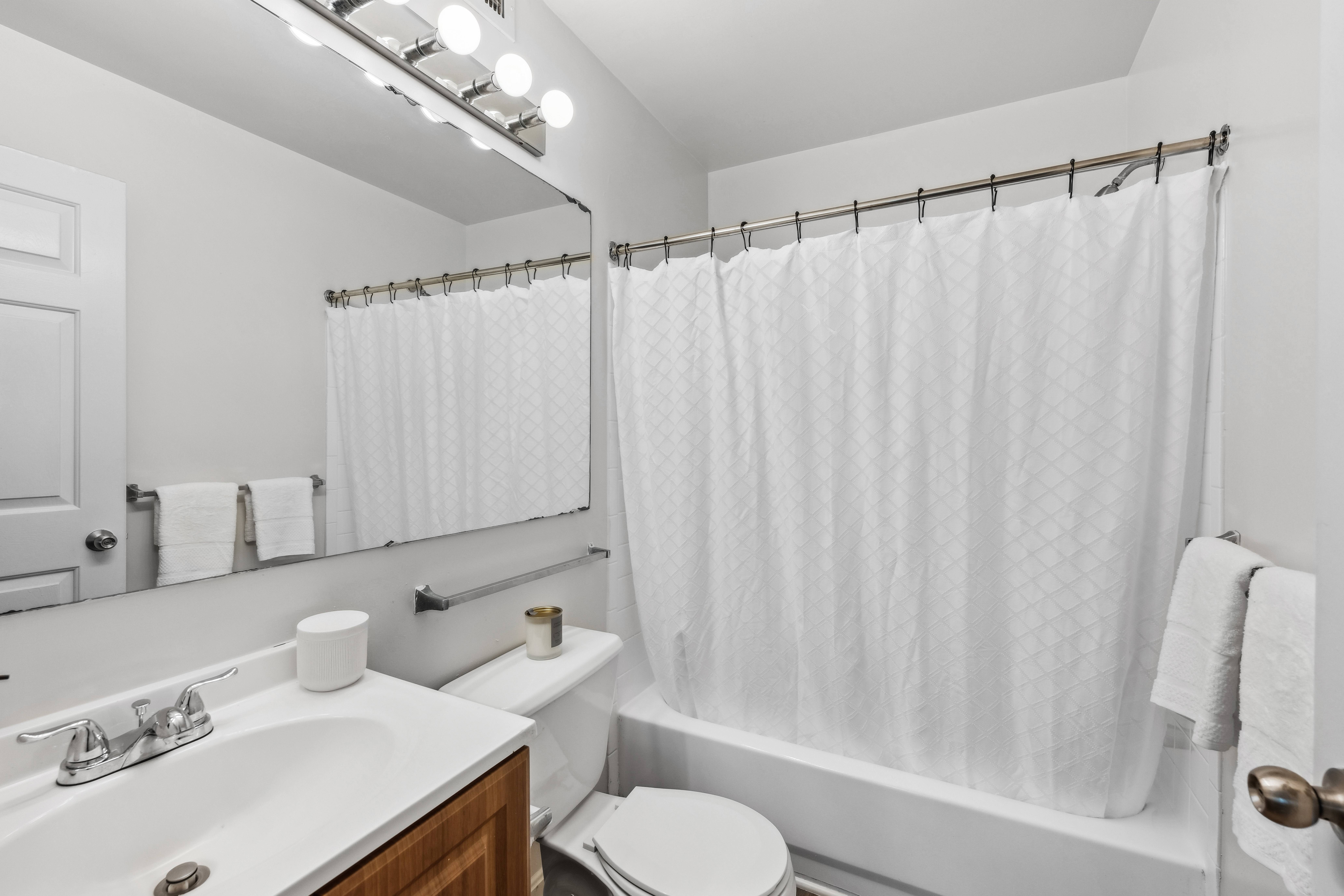 A white bathroom with a toilet, sink, and shower.